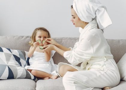 A mother and daughter enjoy a spa day at home, bonding on the couch with cucumber slices.